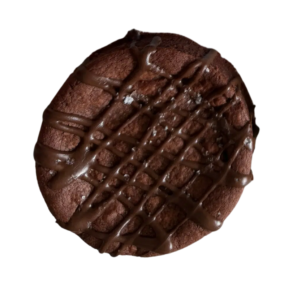 A thick, gourmet gluten-free double chocolate cookie with a dense fudgy texture, finished with a chocolate drizzle and a light dusting of sea salt.