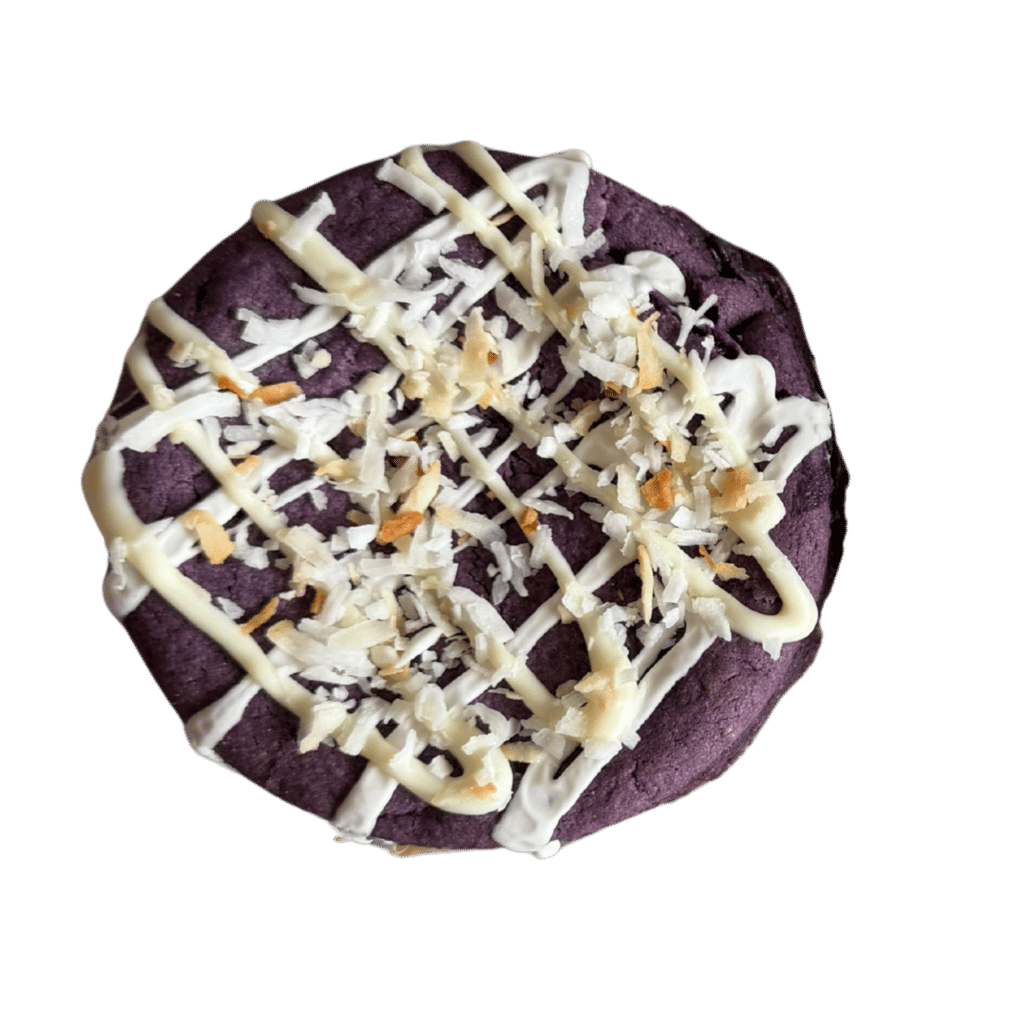 Ube Coconut Bliss | Gluten Free | Coffee House Collection A thick gourmet gluten-free Ube cookie with a vibrant purple center, topped with a white chocolate drizzle and toasted coconut flakes.