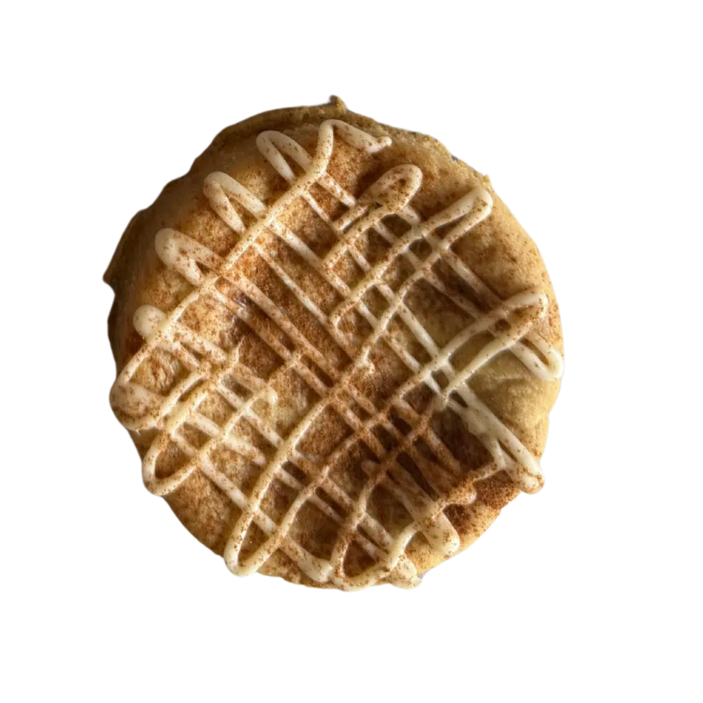 A thick, soft-baked gluten-free snickerdoodle cookie topped with a heavy white chocolate cross-hatch drizzle.